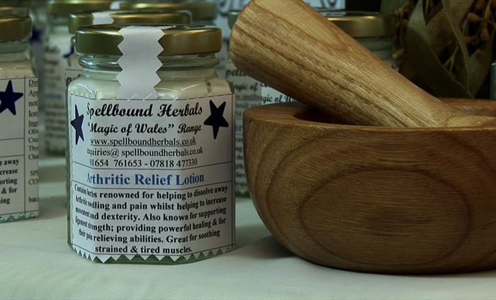A jar of arthritic relief lotion beside a wooden pestle and mortar